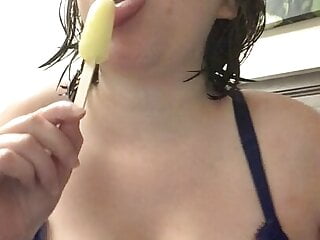 Bored mom with banana popsicle sucking on it